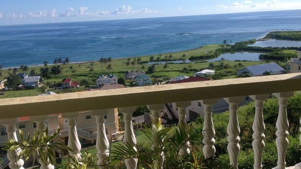 Une vue sur la côte, avec une balustrade de balcon, des maisons et un ciel bleu dégagé.