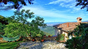 A stone-paved patio with potted plants, overlooking a mountainous landscape and a traditional building with a tiled roof. - Villa Ancora - House with private pool (Cercina)