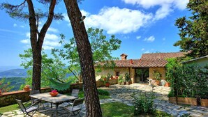 A stone patio with a table and chairs, surrounded by greenery and a stone wall. - Villa Ancora - House with private pool (Cercina)