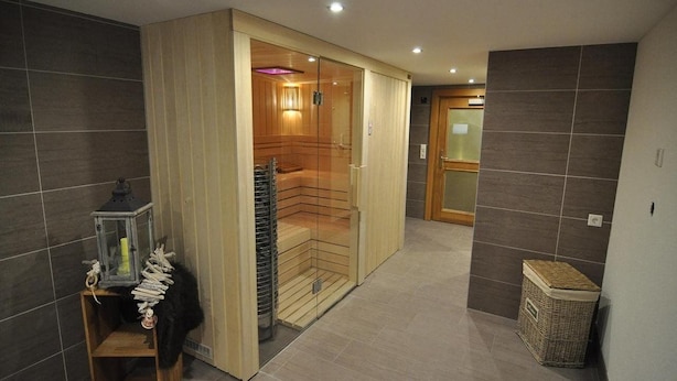 A modern bathroom with a glass-enclosed shower, a wooden vanity, and a wicker basket.
