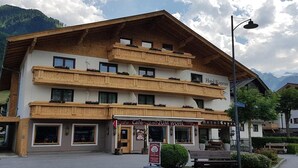 A hotel with a wooden facade, balconies with flower boxes, and a sign for Cafe Zum Wohl.