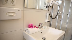 A bathroom with a white sink, a mirror, and a hairdryer mounted on the wall.
