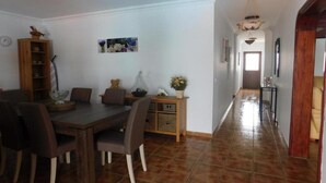 A dining area with a wooden table and chairs, a vase with flowers, and a wooden cabinet with shelves. - Villa Lucky (Tías)