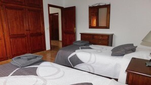 A bedroom with two beds, wooden wardrobe, a dresser, and a mirror. - Villa Lucky (Tías)