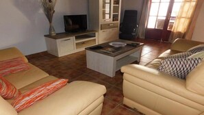 A living room with two beige sofas, a coffee table, a TV on a stand, and a cabinet. - Villa Lucky (Tías)