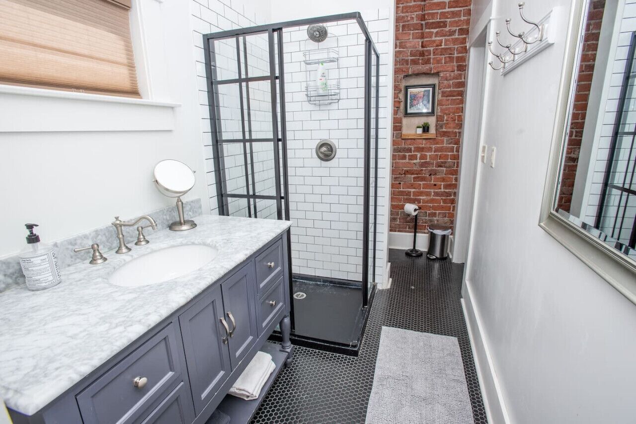 Une salle de bain avec deux lavabos, un espace douche et une petite fenêtre.