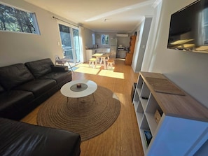 A modern living room with a black leather sofa, a white coffee table, and a wooden floor. - A beautiful chalet in a secluded bush environment, only a short walk to town. (Denmark)