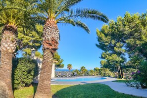 A swimming pool surrounded by palm trees and a grassy area. - Large and comfortable villa in Denia, Costa Blanca, Spain  with private pool for 6 persons (Denia)