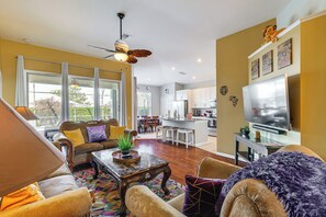 A spacious living area with a sofa, armchair, coffee table, and a ceiling fan.