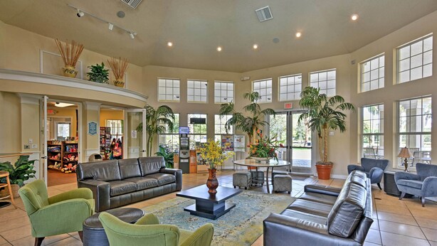 A spacious lobby with a leather sofa, green armchairs, a coffee table, and a large window overlooking the outdoors. - Pool, Themed Rooms & Arcade: Disney Escape (Kissimmee)