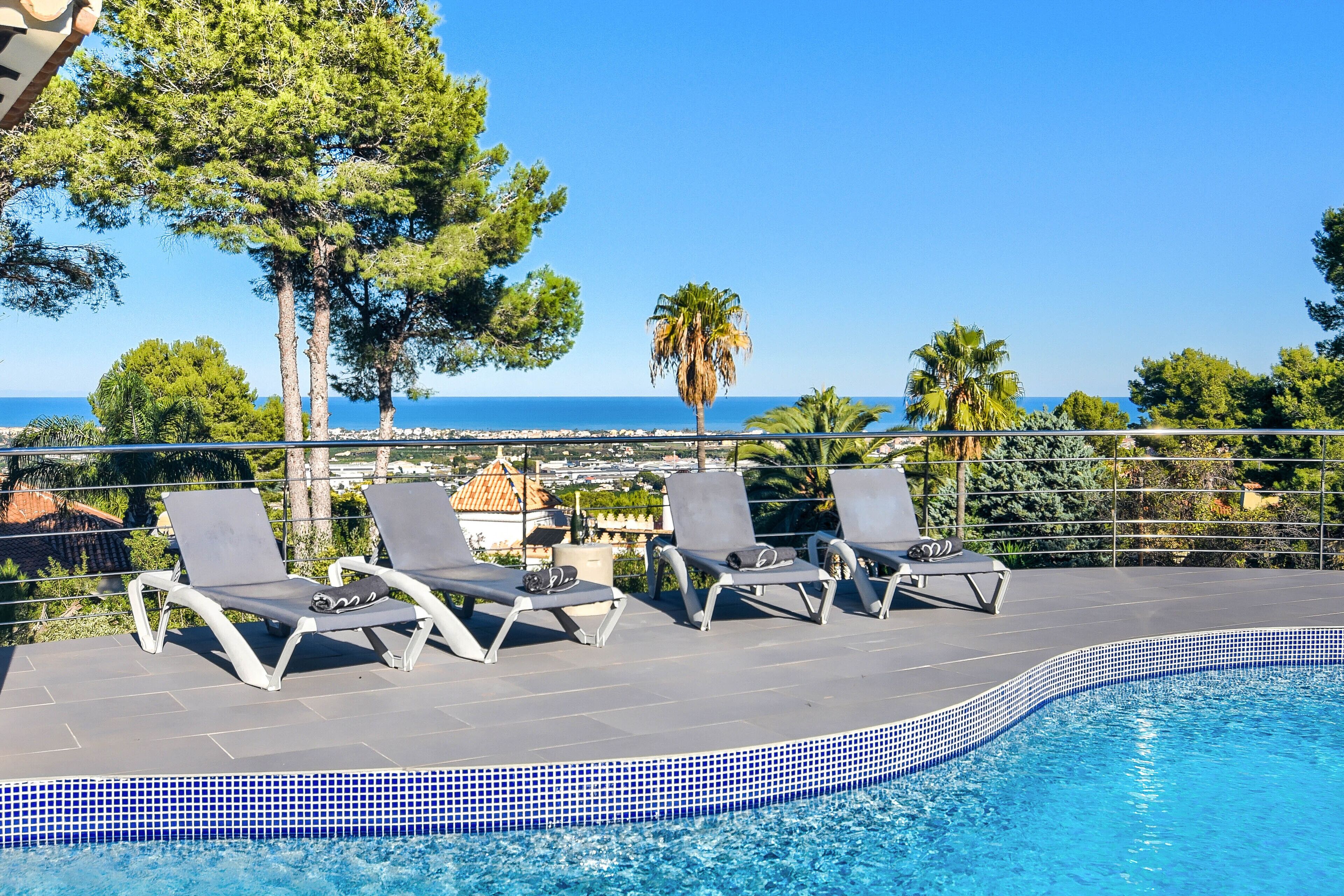 A poolside area with lounge chairs and a view of the sea.