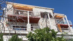 A multi-story building with balconies, some with railings and others with open sides. - Apartments Neve (Dubrovnik)