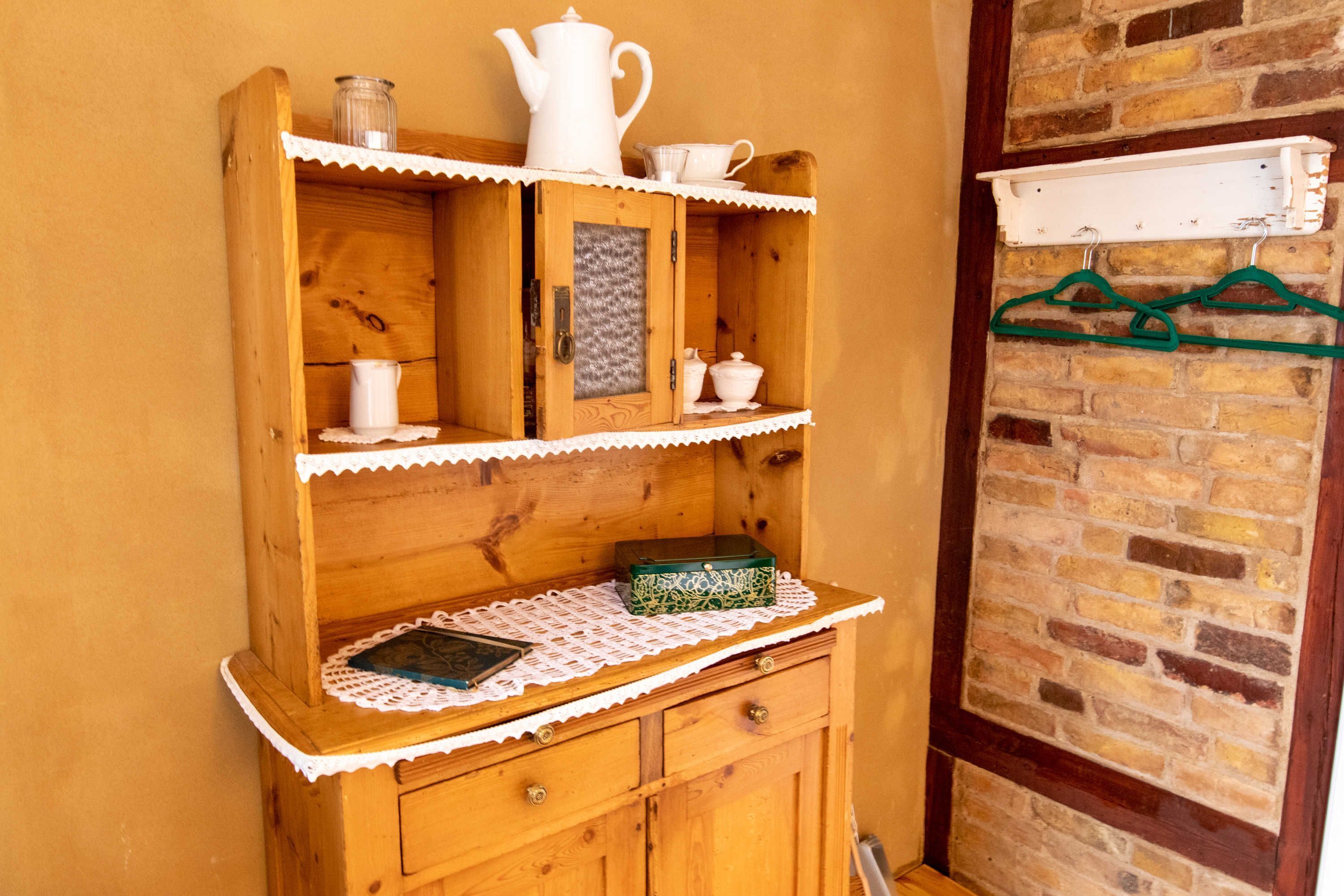 Ein Holzschrank mit Regalen, Schubladen und einer Spitzendecke.