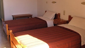 Una habitación con dos camas de madera, una mesita de noche también de madera y un banco.