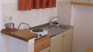 Una kitchenette pequeña con estufa, pileta y mesada de madera.