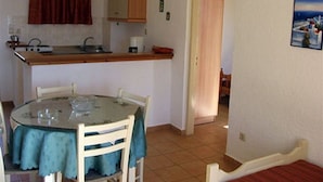 Una pequeña cocina con una mesa y sillas, un mueble de madera y un cuadro en la pared.
