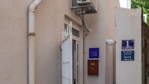 A narrow hallway with a white door, a small air conditioning unit mounted on the wall, and a sign indicating room number 1. - Rooms Edna (Dubrovnik)