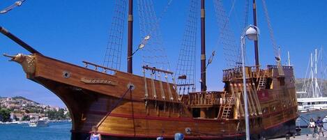 Un barco de madera grande atracado en un puerto con cielo azul despejado.