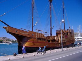 Un barco de madera grande atracado en un puerto con cielo azul despejado.