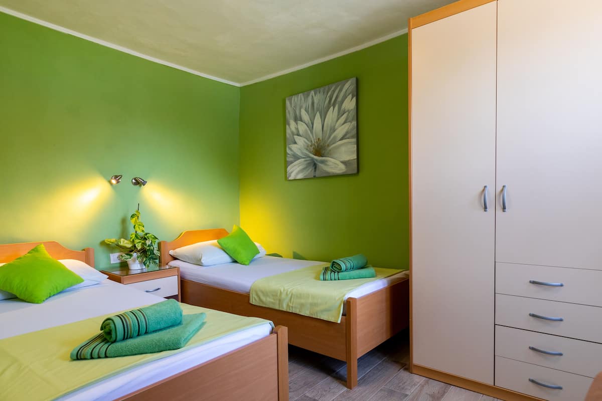 Habitación de hotel con dos camas, un armario y un cuadro en la pared.