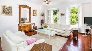 Una sala de estar con un sofá blanco, una mesa de centro, un espejo grande y un televisor.