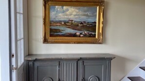 Um corredor com um armário cinzento e um quadro de uma paisagem.