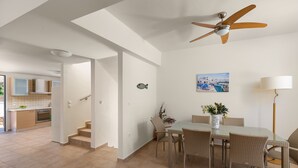 Una cuina moderna amb forn integrat i zona de menjador amb mobiliari de vimet i taula de vidre.