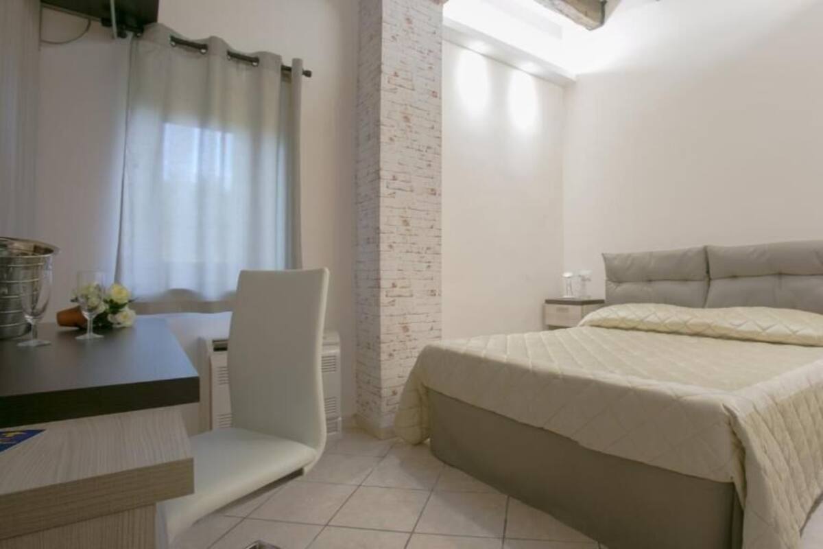 Quarto com cama, cadeira, escrivaninha e mesa de cabeceira.