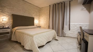 A bedroom with a bed, a nightstand, a lamp, a wardrobe, and a curtain.