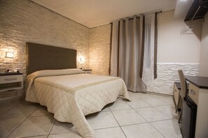 Ein Schlafzimmer mit Bett, Nachttisch, Lampe, Kleiderschrank und Vorhang.