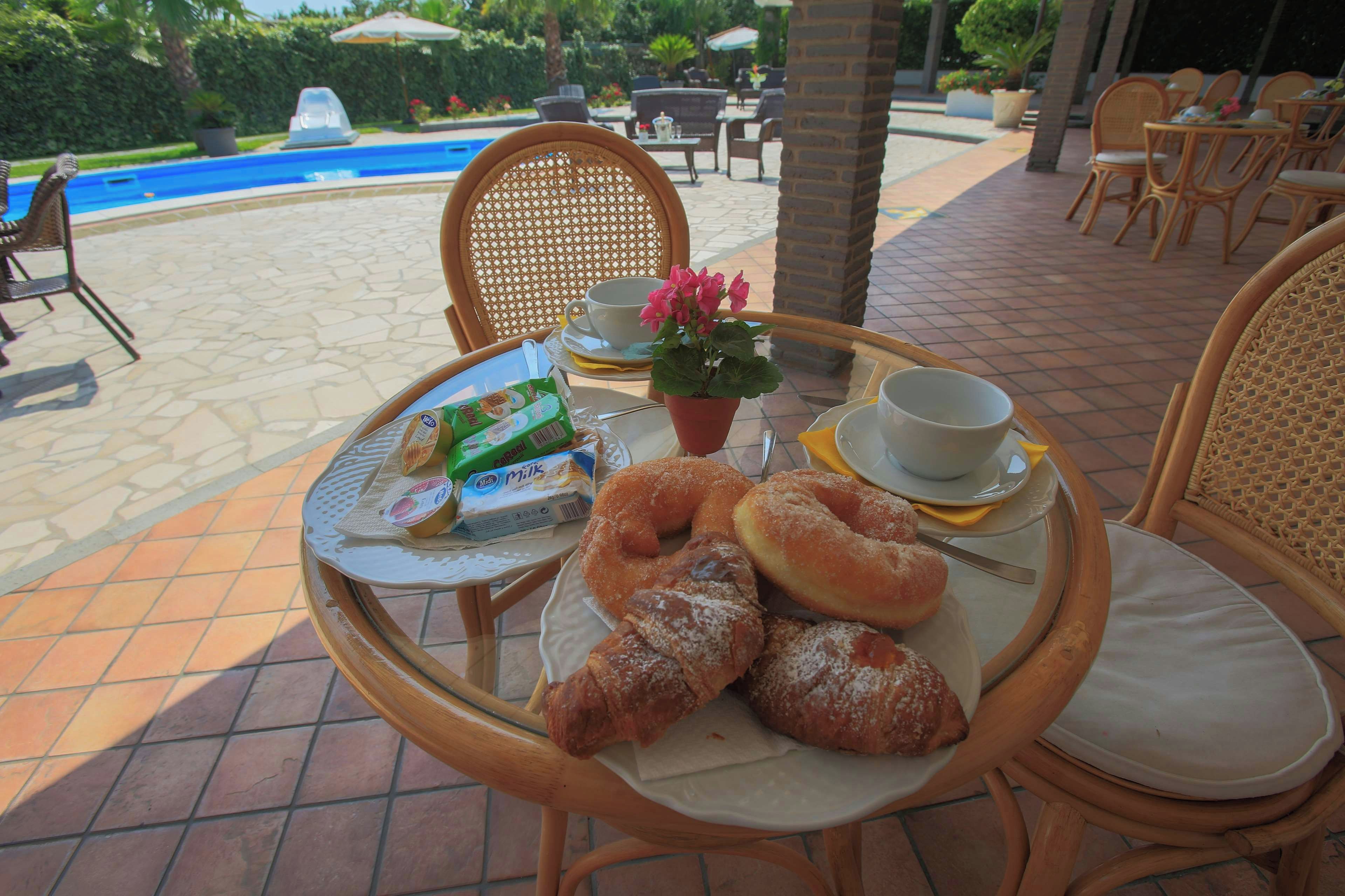 A round table with a plate of pastries, a cup, and a small potted plant.