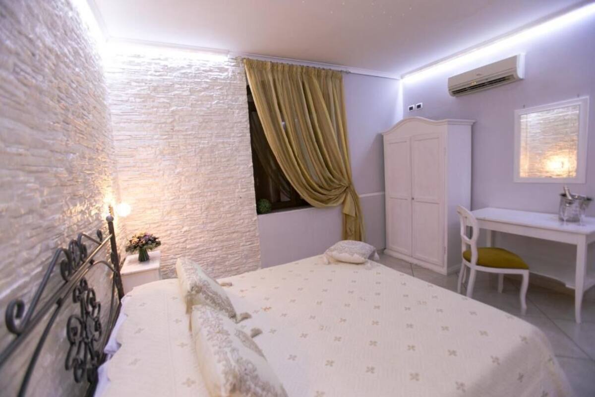 Quarto com cama, escrivaninha, guarda-roupa e janela com cortinas.