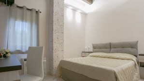 A bedroom with a bed, a chair, a table, and a nightstand. - La Fenice (Boscoreale)
