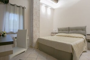 Ein Schlafzimmer mit Bett, Stuhl, Tisch und Nachttisch.