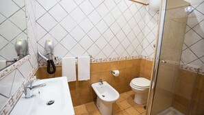 Une salle de bain comprenant un lavabo, un bidet, des toilettes et une douche séparée par une paroi en verre.