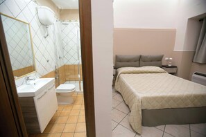 A hotel room with a bathroom, a bed, a bedside table, and a mirror. - La Fenice (Boscoreale)