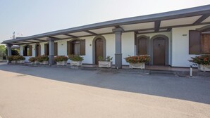 Une rangée de pièces reliées par une galerie couverte, chacune ayant une porte et une fenêtre.