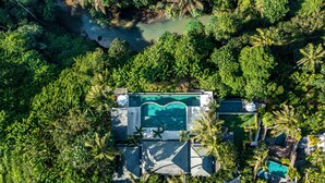 Ein Luftbild eines Anwesens mit Swimmingpool, umgeben von üppiger Vegetation und einem Fluss.