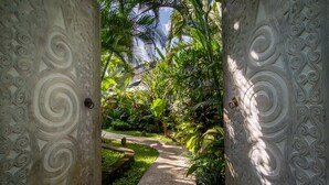Ein Weg, der durch einen üppigen Garten führt, dessen Wände kunstvolle Steinmetzarbeiten zeigen.
