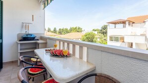 Ein Balkon mit Frühstückstisch, mit Wassermelonenstücken und Orangensaft, mit Blick auf eine Wohngegend.
