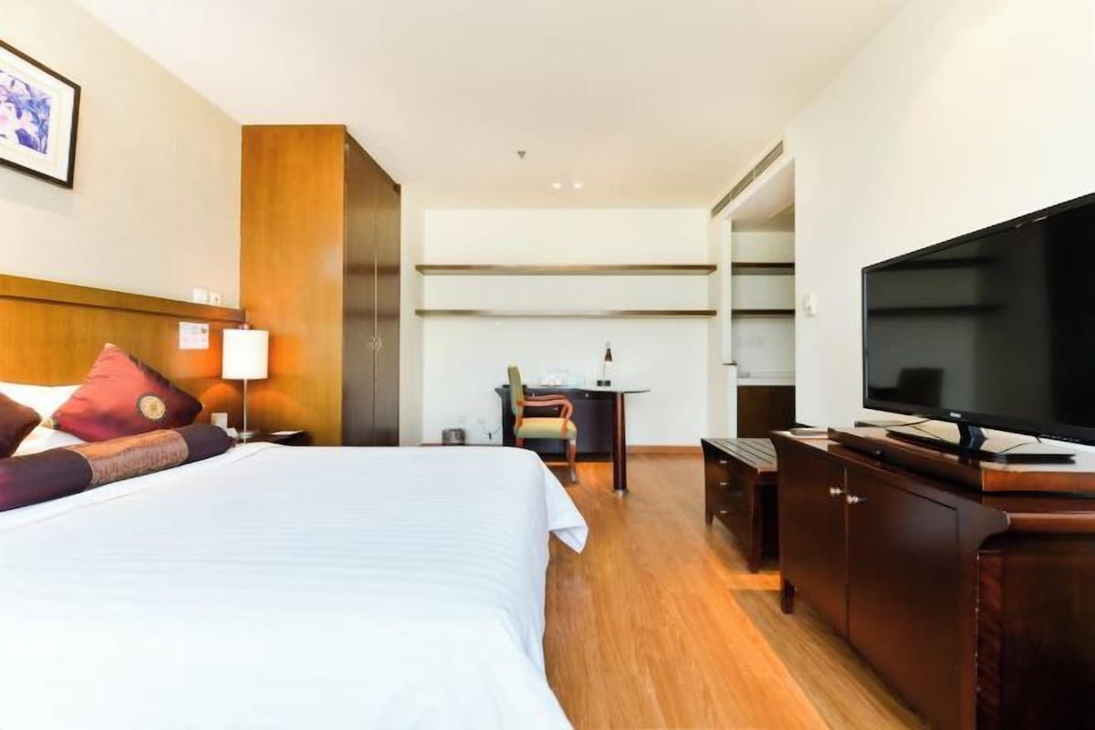 A hotel room with a bed, a desk, a television, and a chair.