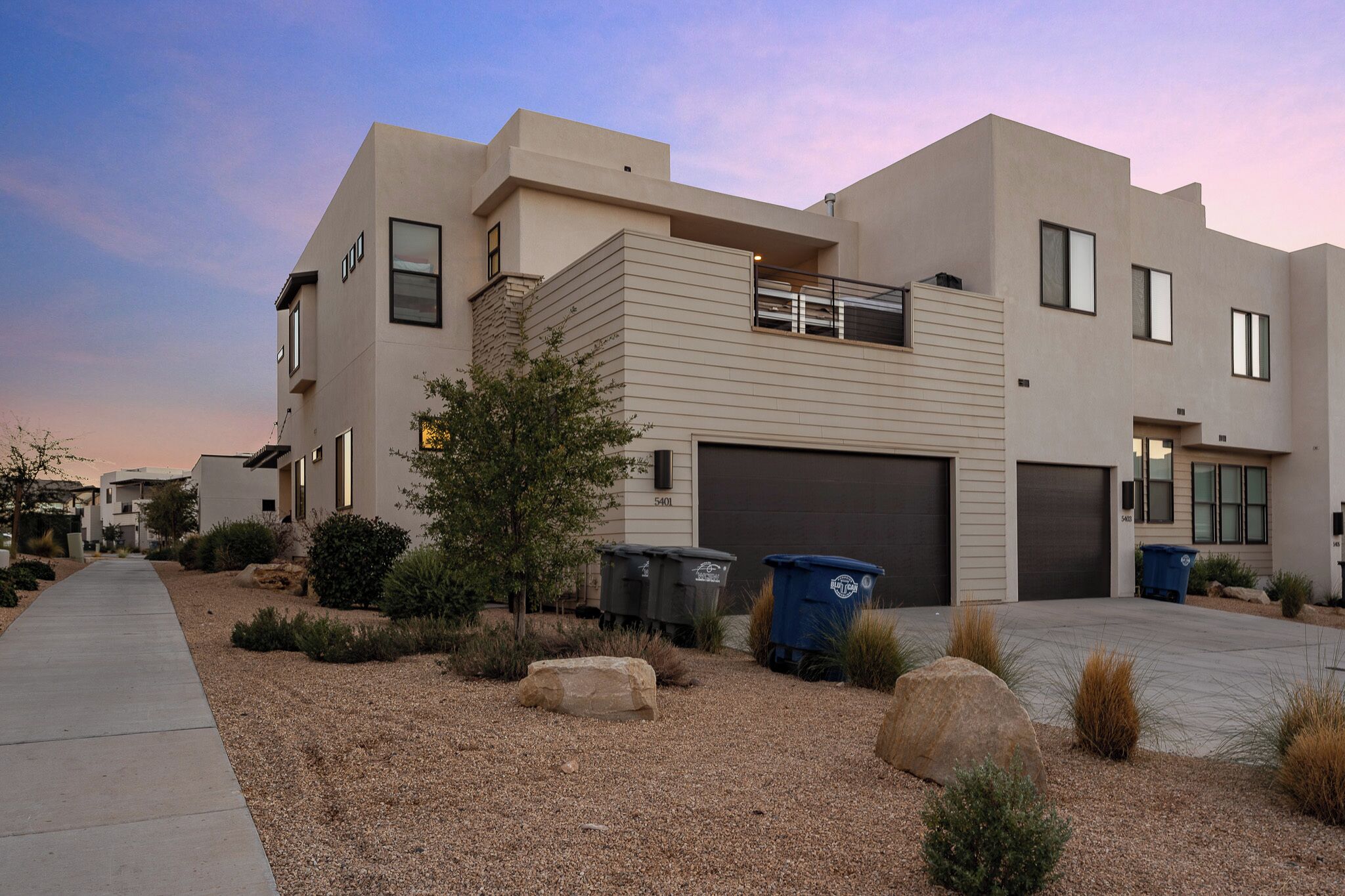 A modern residential building with a garage, a covered walkway, and a landscaped driveway.