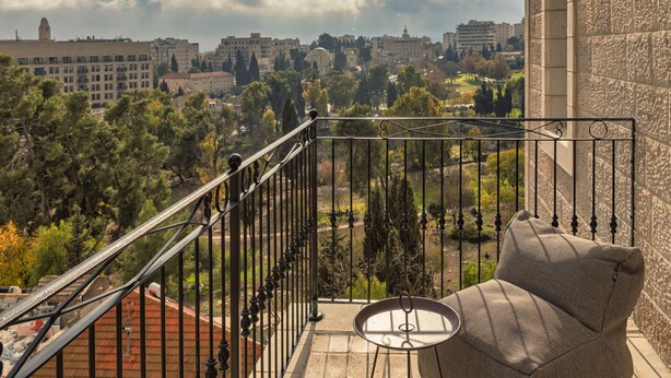 Un balcón con vistas a un paisaje urbano, que incluye edificios y árboles.