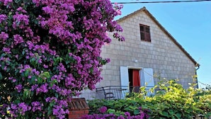 Una casa con fachada de ladrillo, un pequeño balcón y una ventana con contraventanas.