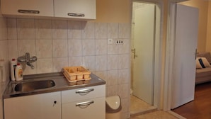 Una cocina compacta con fregadero, armarios y un cubo de basura.