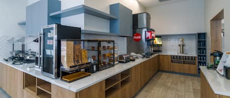 A modern kitchen area with a white countertop, wooden cabinets, and a herringbone-patterned backsplash.