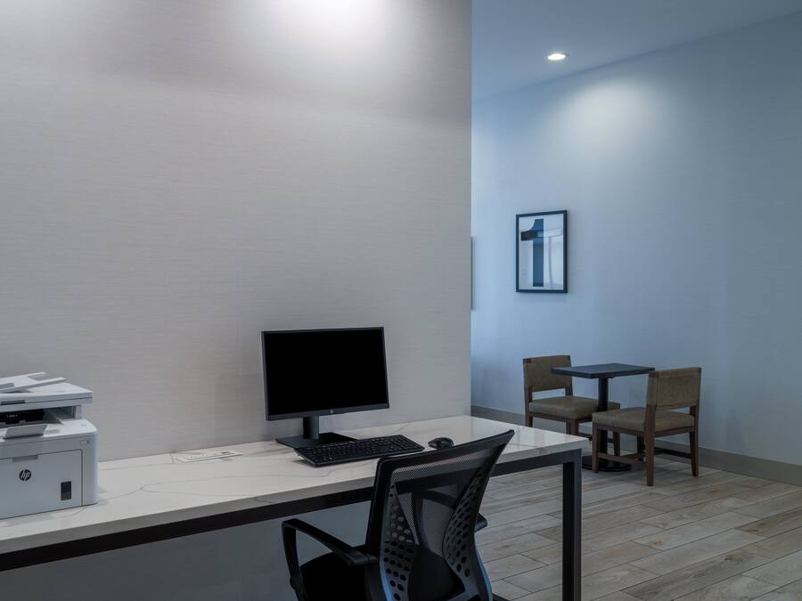 A modern office space with a desk, HP printer, computer monitor, keyboard, and a chair.