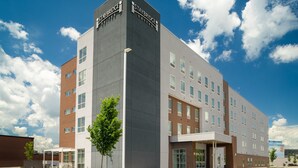 Een Staybridge Suites hotel met een modern design, bestaande uit een gevel van baksteen en glas, meerdere verdiepingen en een overdekt entreegebied.