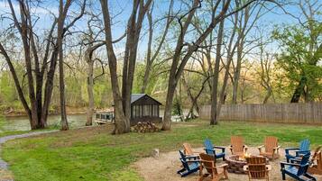 A backyard with a fire pit, outdoor furniture, a shed, and a wooden fence.