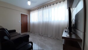 Ein Wohnzimmer mit einer Couch, einem Fernseher und einer Tür.